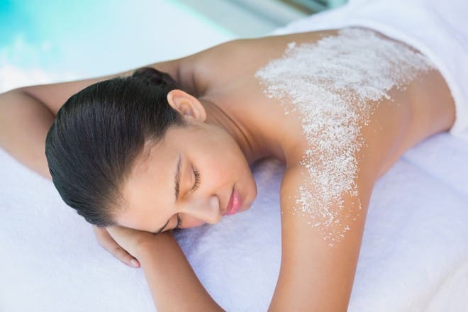 Calm brunette lying on towel with salt treatment on back outside